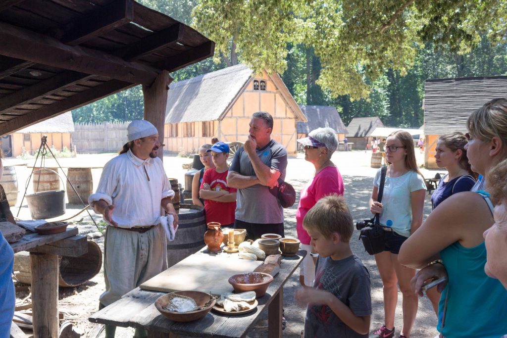 A docent at Jamestown Settlement's fort shows onlookers how he prepares food for the Virginia Company outpost. (Kevin Kaiser | Travel Beat Magazine)