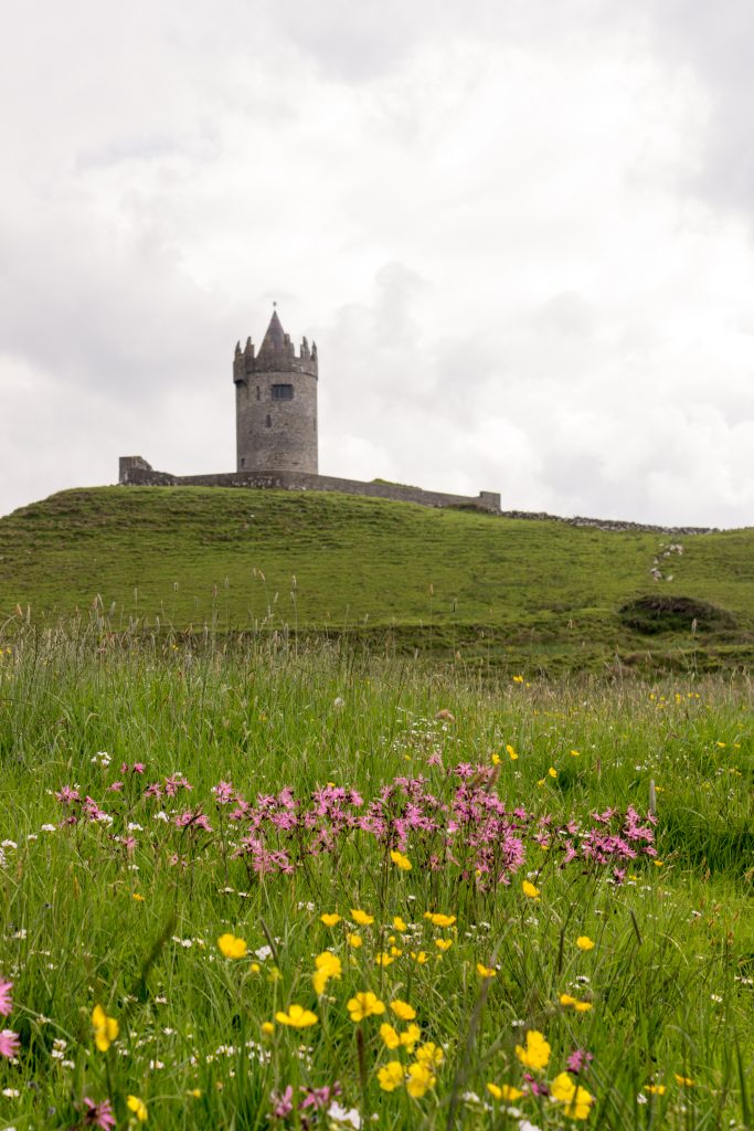 Doonagore Castle is Doolin’s iconic tower house castle, built around 1500 on the western shore of Ireland. To get a unique vantage point of this castle, one must find a spot of color on a cloudy day. This time the color is found in a field of wildflowers. (Kevin Kaiser | Travel Beat Magazine)